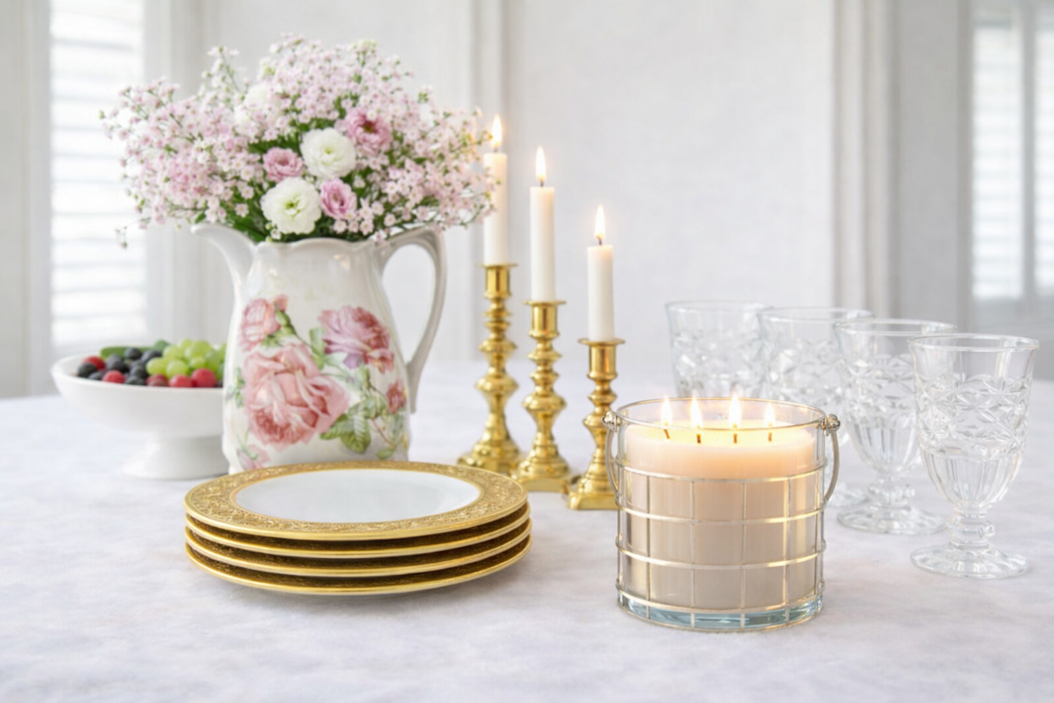 Decorative table setting with candles, plates, and flowers on a white surface.